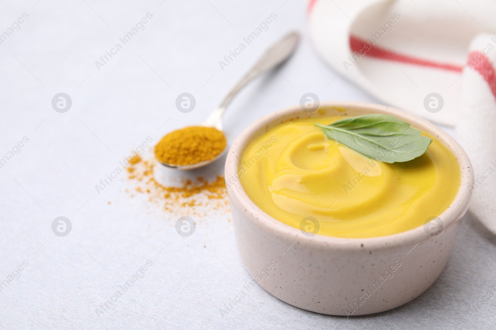 Photo of Tasty curry sauce, powder and basil leaf on light table, closeup. Space for text