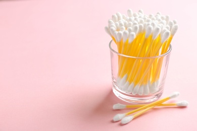 Photo of Glass with cotton swabs on color background. Space for text