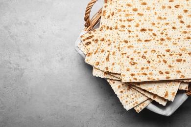Photo of Traditional matzos in basket on light grey table, top view. Space for text