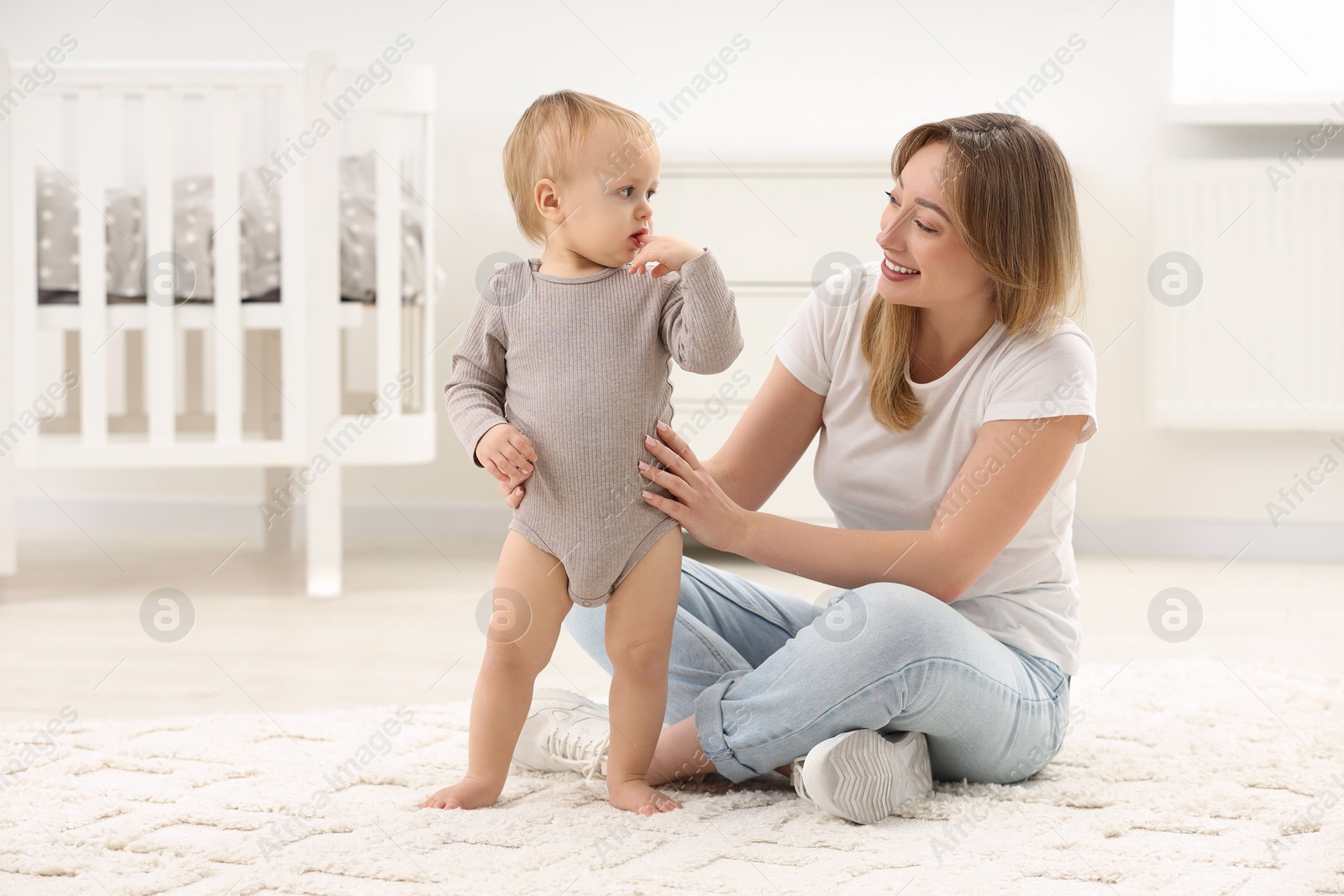 Photo of Mother with her little son on rug at home