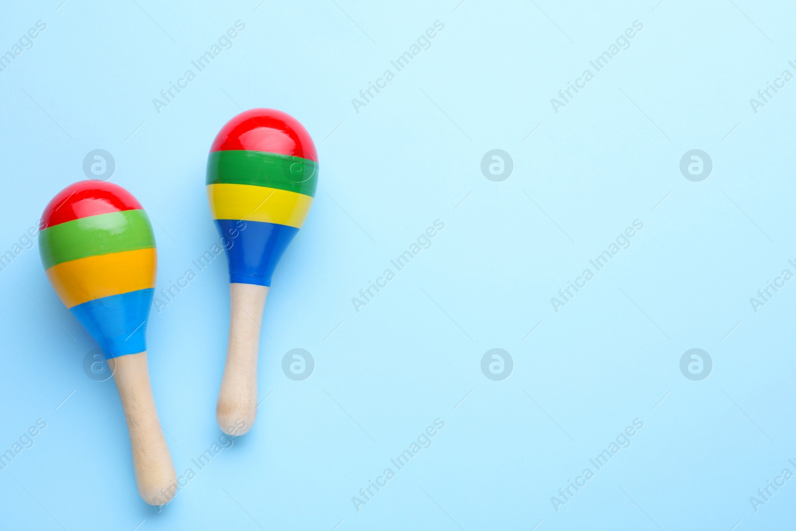 Photo of Colorful maracas on light blue background, flat lay with space for text. Musical instrument