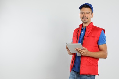 Photo of Happy young courier with tablet on white background. Space for text
