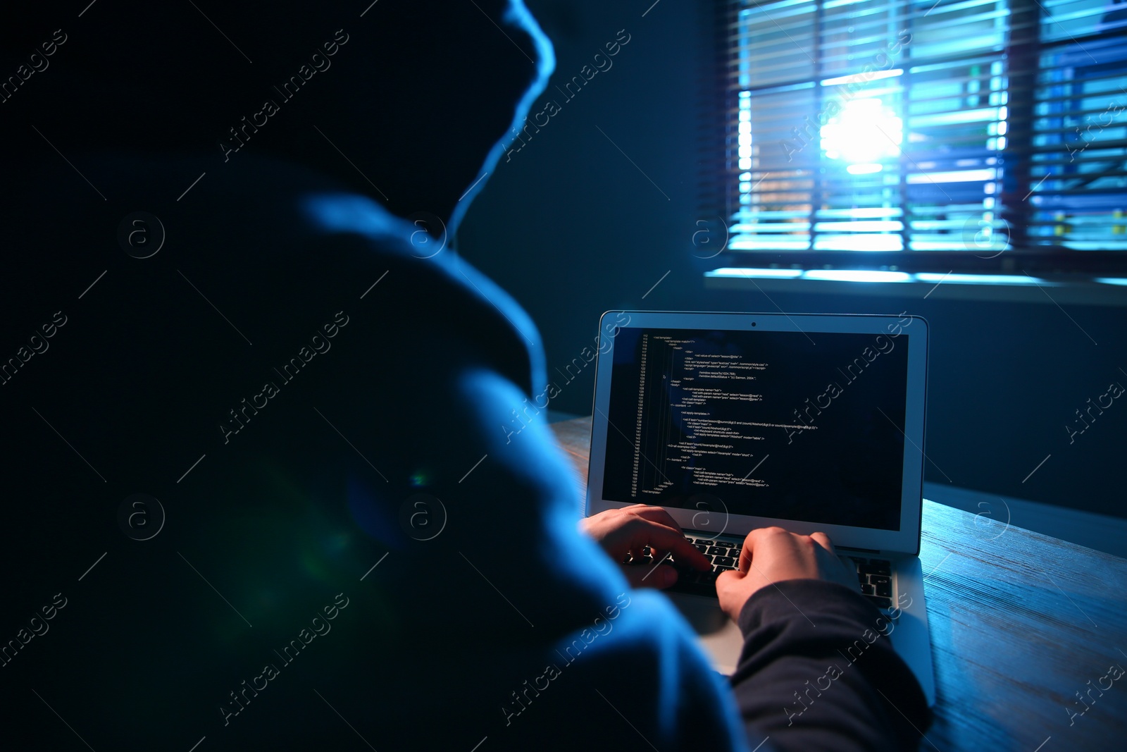 Photo of Hacker with laptop in dark room. Cyber crime