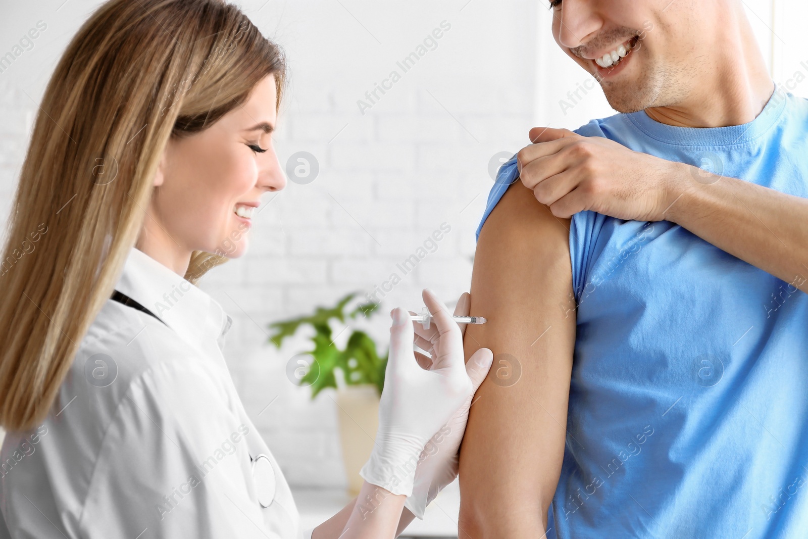 Photo of Doctor vaccinating male patient in clinic