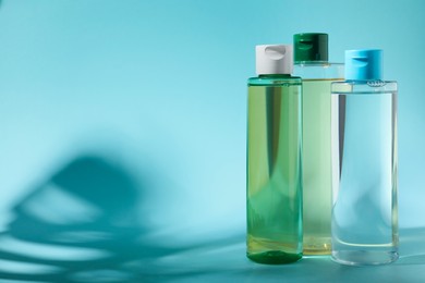 Photo of Bottles of micellar water on light blue background. Space for text