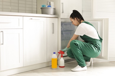 Professional janitor cleaning modern fridge in kitchen