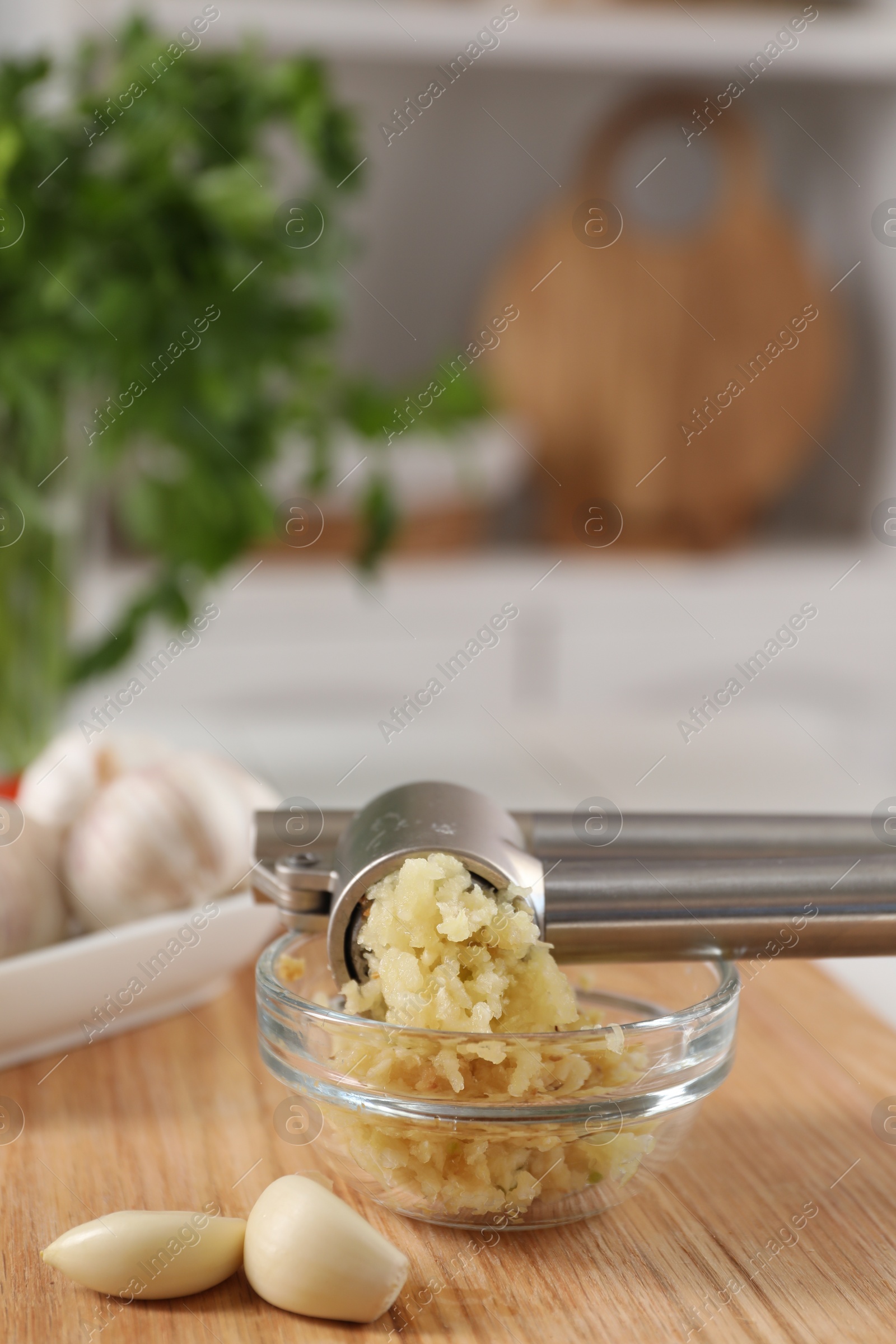 Photo of Garlic press, cloves and mince on wooden table in kitchen, closeup