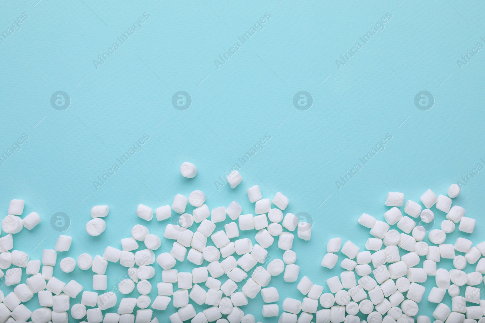 Photo of Delicious marshmallows on light blue background, flat lay. Space for text