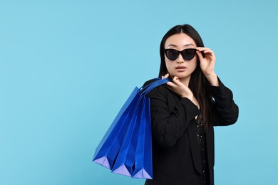 Photo of Beautiful woman with shopping bags on light blue background. Space for text