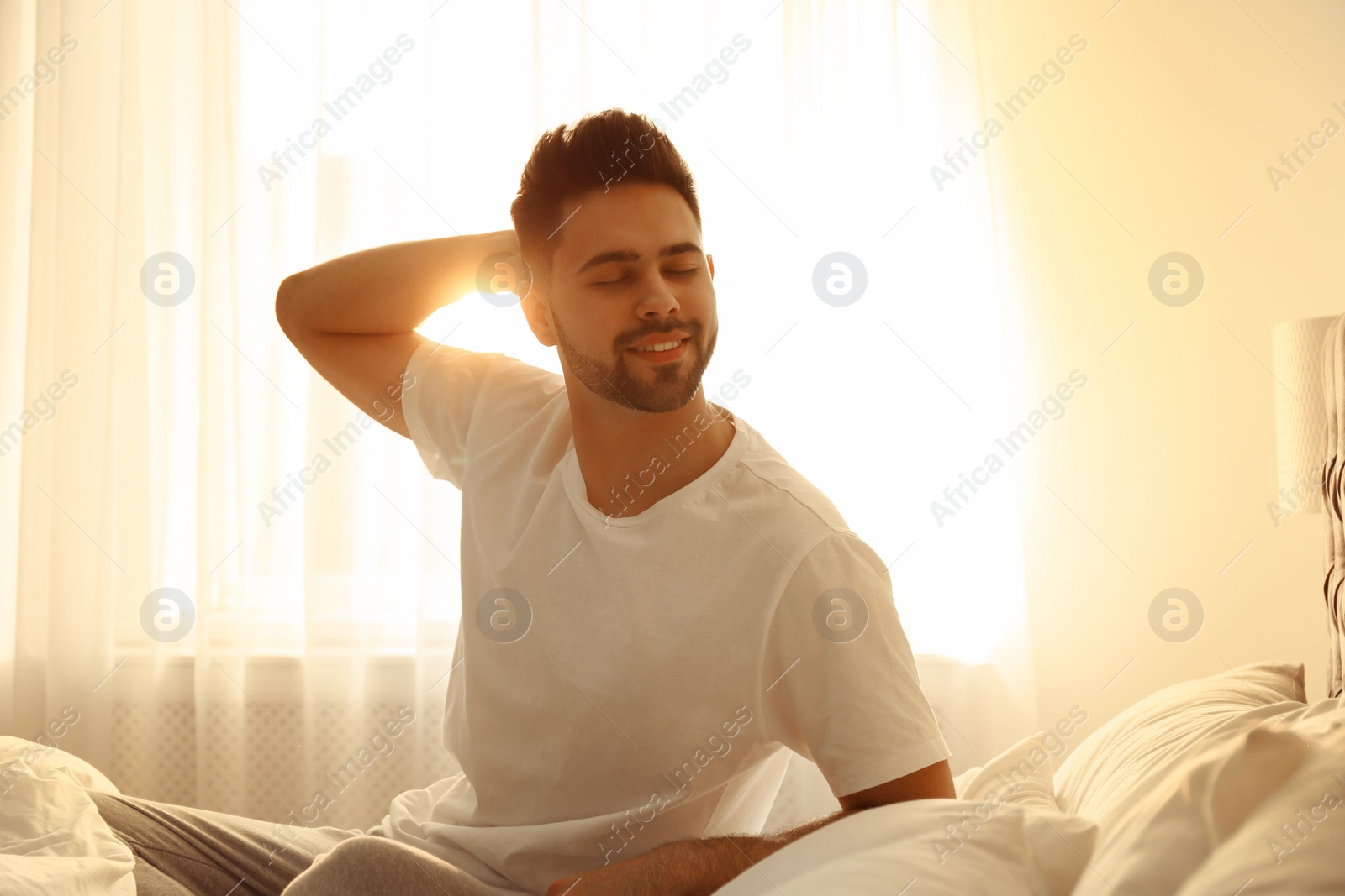 Photo of Young man awakening on bed at home. Lazy morning