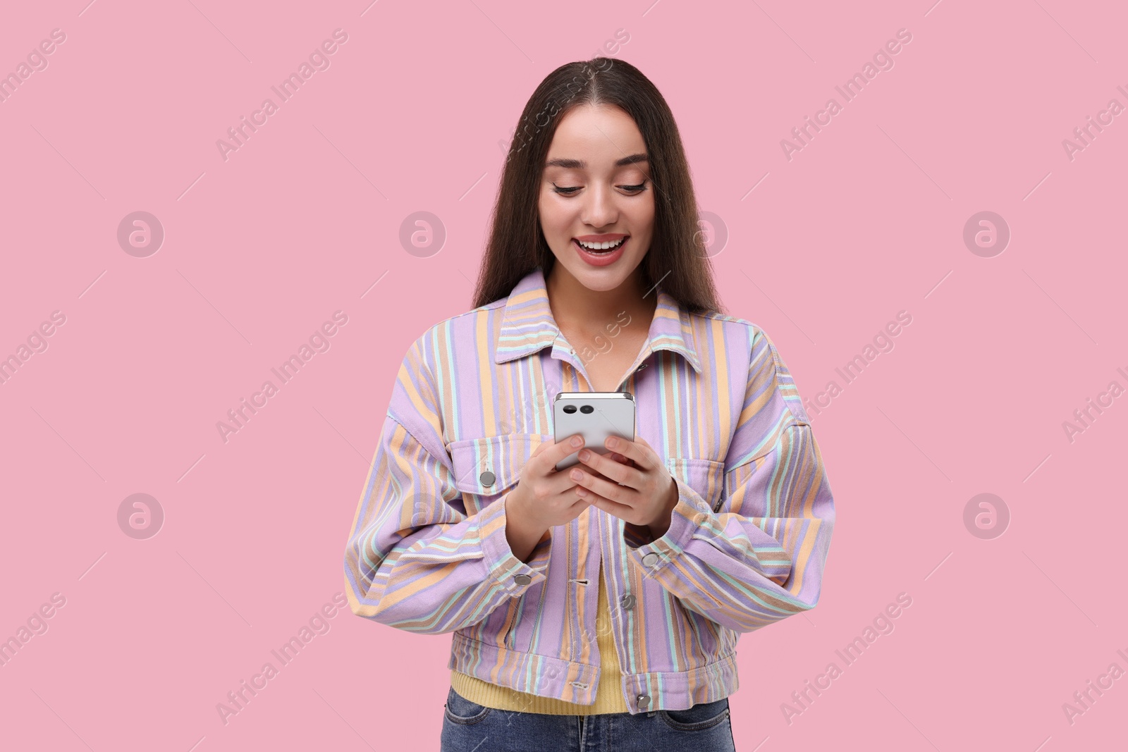 Photo of Happy woman sending message via smartphone on pink background