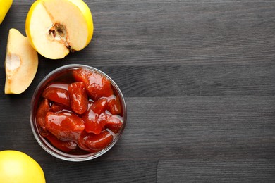 Photo of Quince jam in glass bowl and fresh raw fruits on grey wooden table, flat lay. Space for text