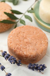 Photo of Solid shampoo bar and lavender on light table, closeup