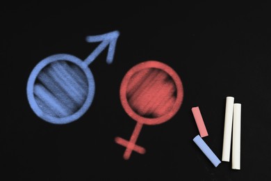 Sex education. Pieces of chalk, drawn female and male gender signs on blackboard, top view