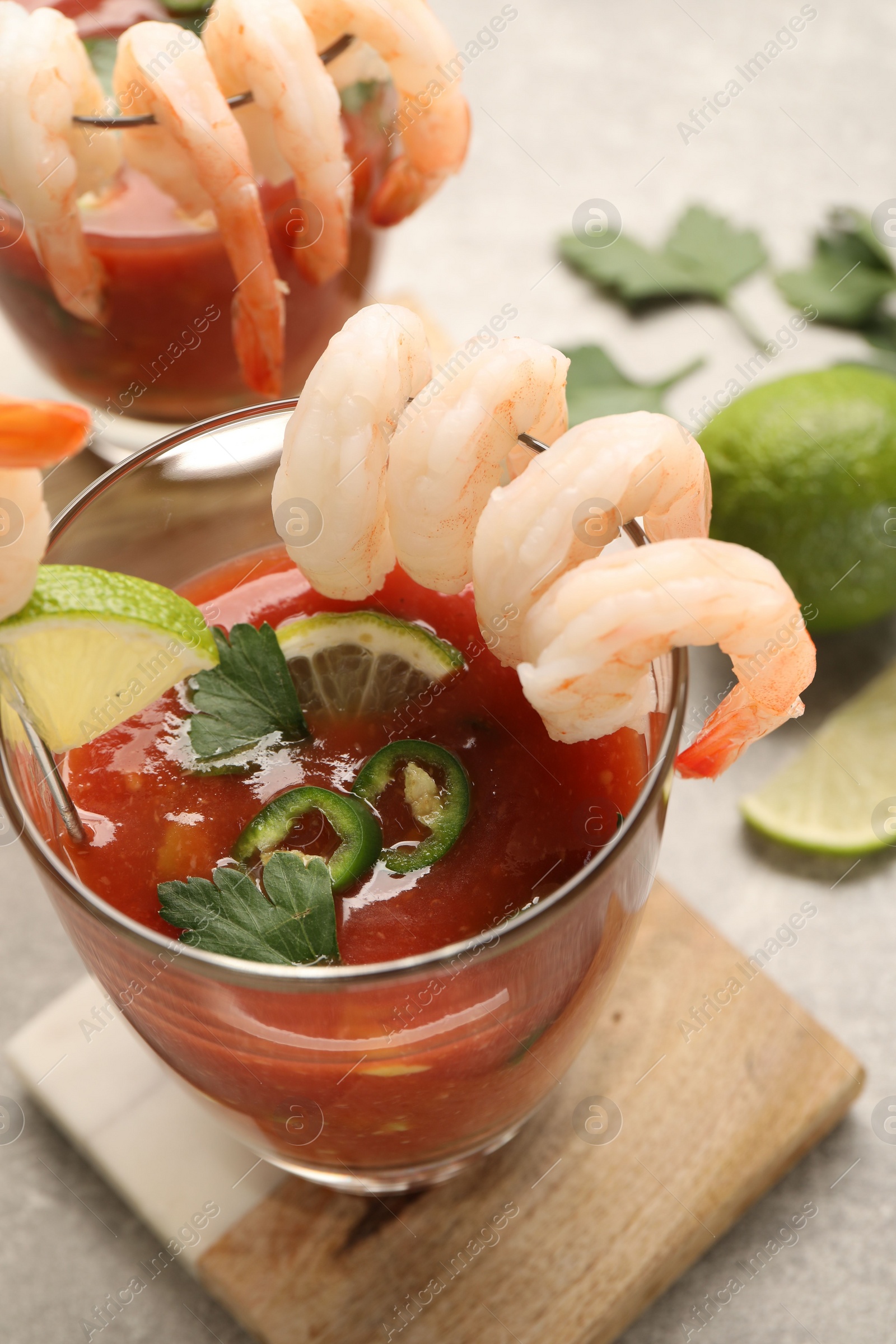 Photo of Tasty shrimp cocktail with sauce in glasses and lime on light table, closeup