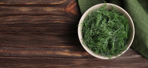 Image of Fresh dill in bowl on wooden table, top view. Banner design with space for text