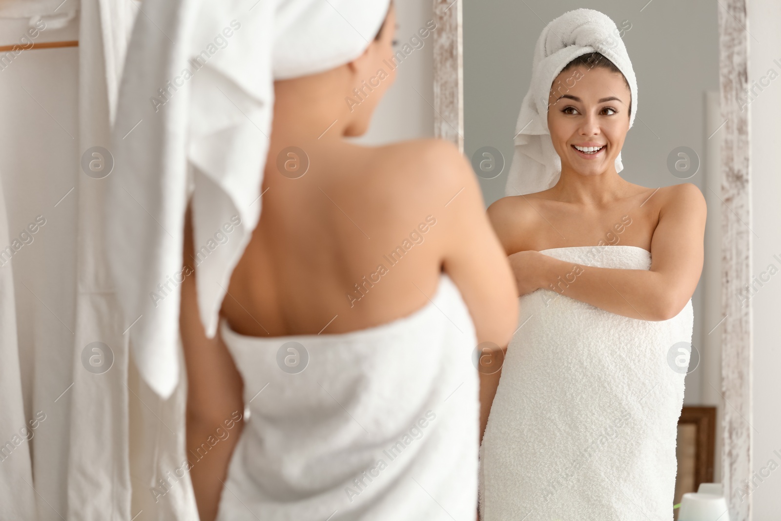 Photo of Beautiful young woman looking at herself in mirror indoors