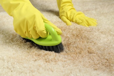 Woman removing stain from beige carpet, closeup