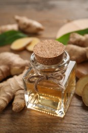 Photo of Glass bottle of essential oil and ginger root on wooden table