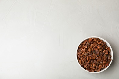 Bowl with pine nuts on light background, top view. Space for text