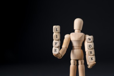Photo of Life work balance concept. Wooden mannequin holding cubes on black background, space for text