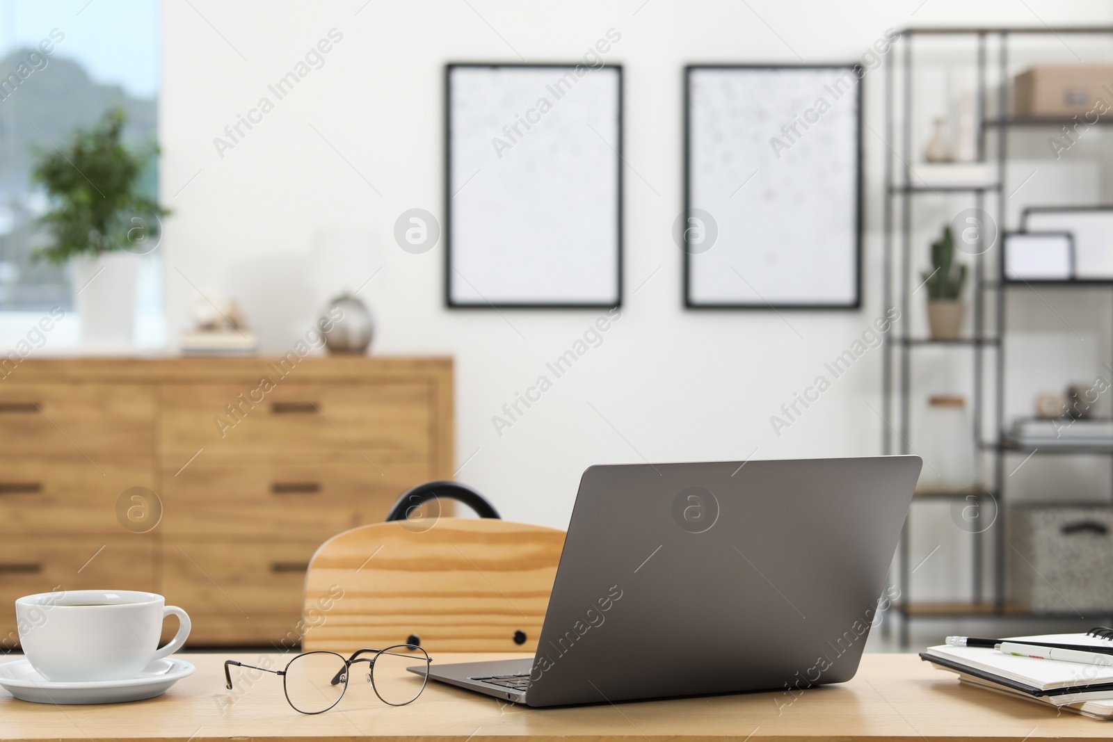 Photo of Home workspace. Laptop, glasses, cup of coffee and stationery on wooden desk in room. Space for text