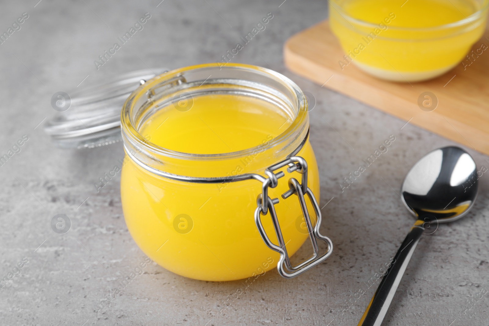 Photo of Glass jar of Ghee butter on grey table, closeup