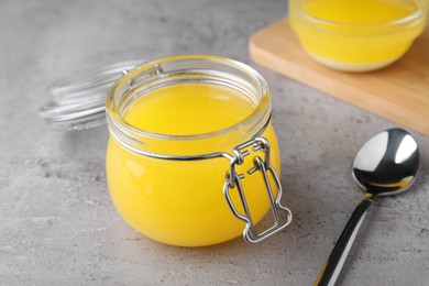 Glass jar of Ghee butter on grey table, closeup