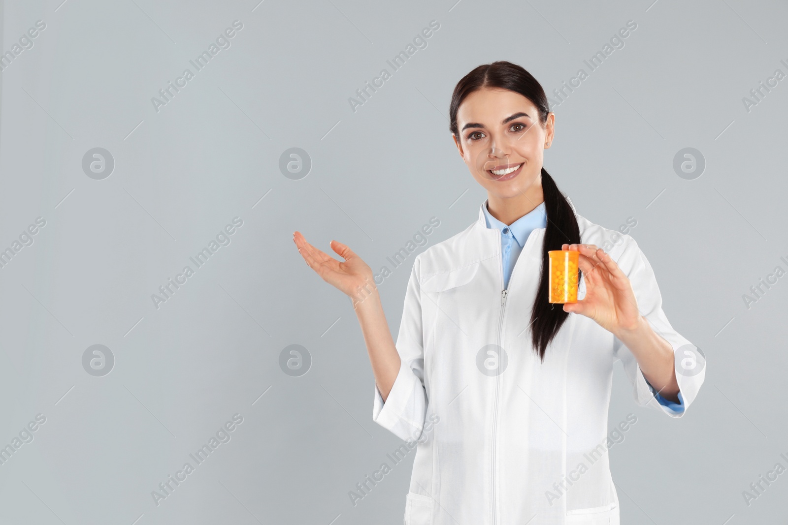 Photo of Professional pharmacist with pills on light grey background. Space for text