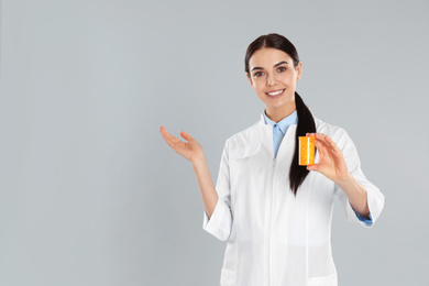 Photo of Professional pharmacist with pills on light grey background. Space for text