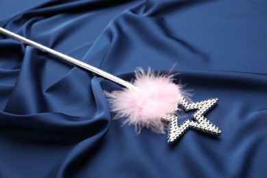 Photo of Beautiful silver magic wand with feather on blue fabric