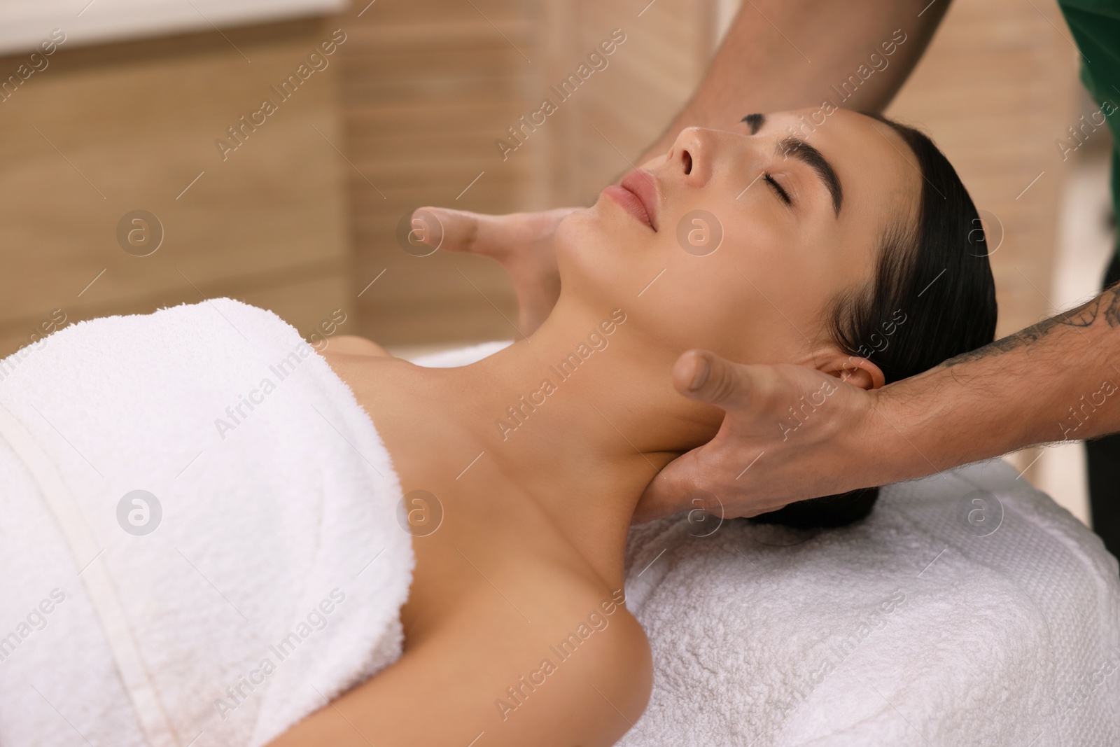 Photo of Woman receiving professional neck massage on couch indoors