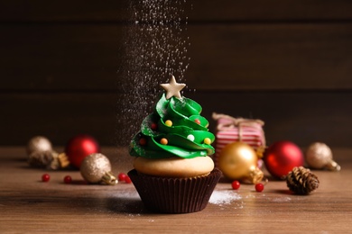 Sprinkling powdered sugar on Christmas tree shaped cupcake