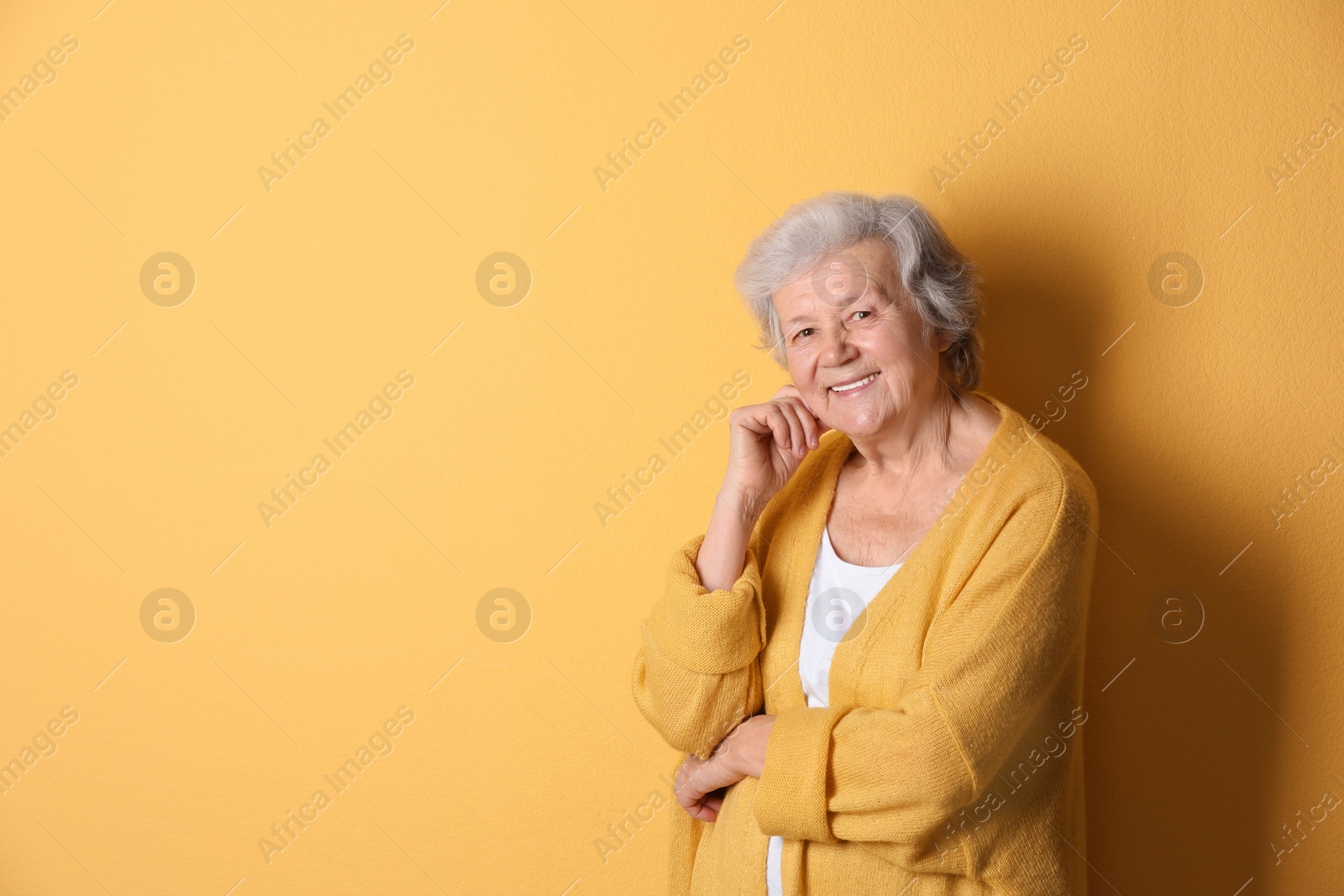 Photo of Portrait of grandmother in stylish clothes on color background, space for text
