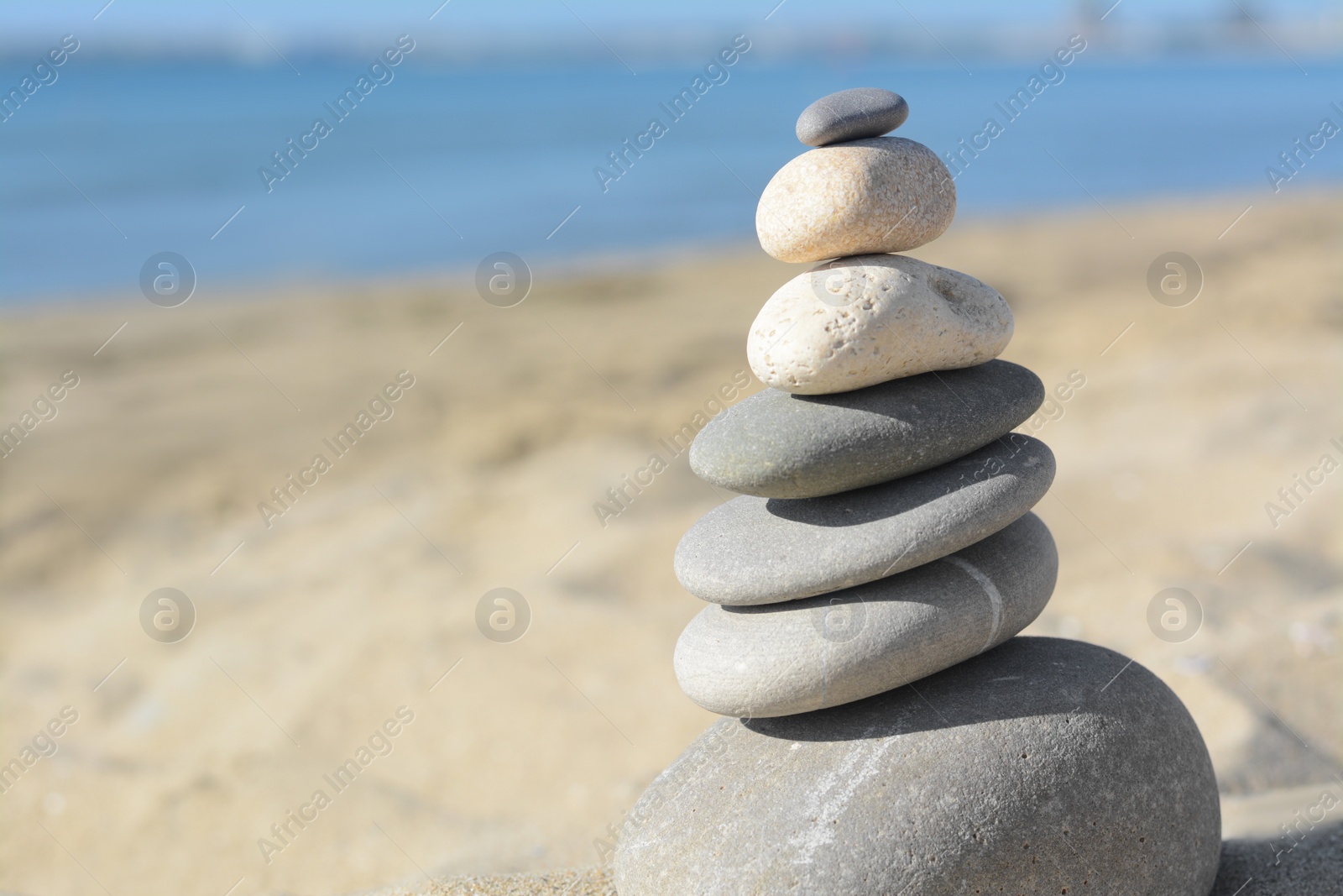 Photo of Stack of stones on sandy beach, closeup. Space for text