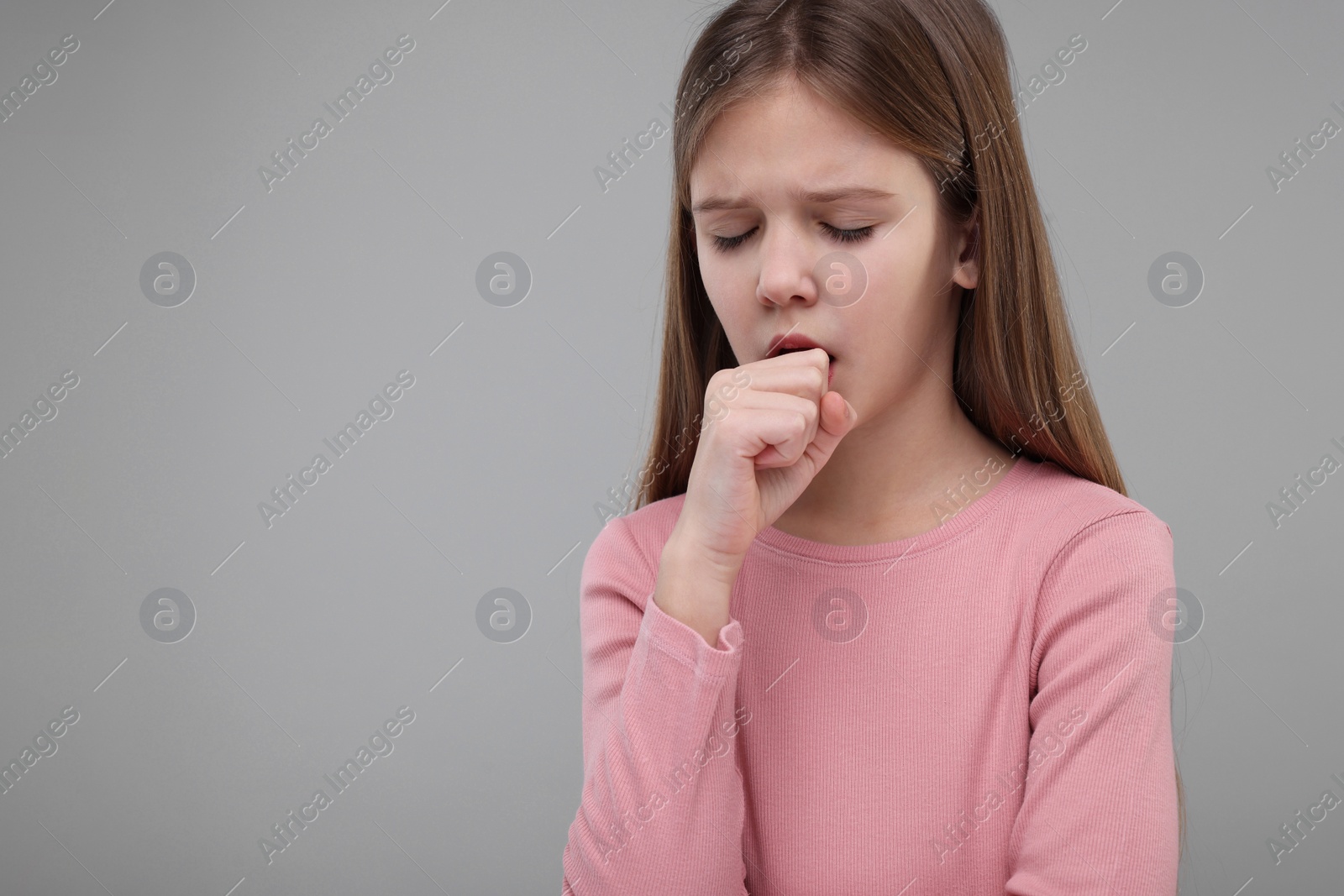 Photo of Sick girl coughing on gray background, space for text