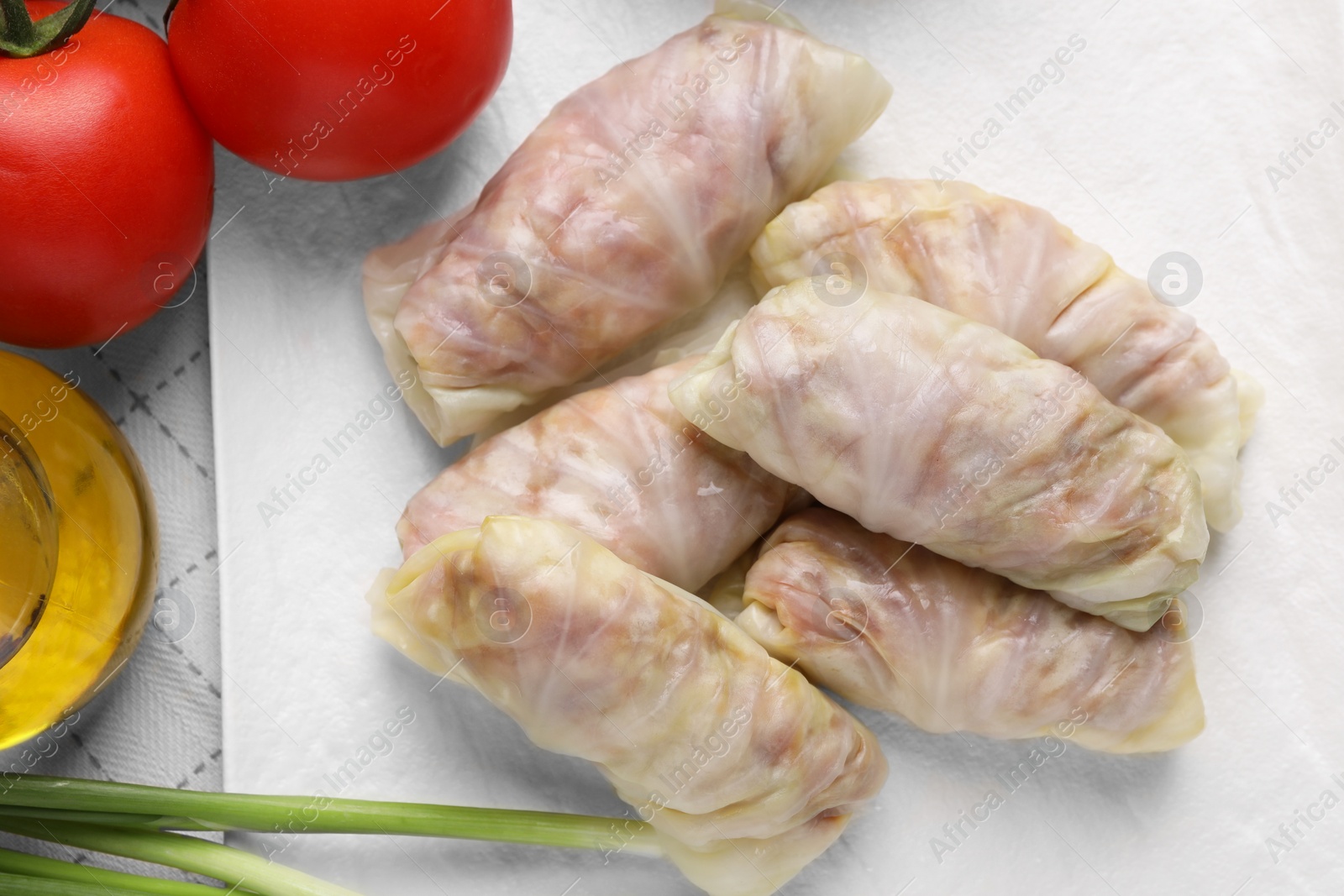 Photo of Uncooked stuffed cabbage rolls and ingredients on table, flat lay