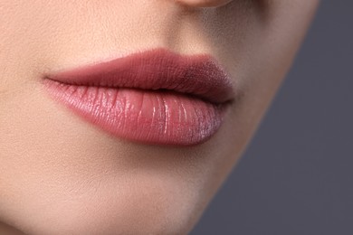 Photo of Woman with beautiful lips on grey background, closeup