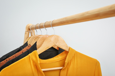 Photo of Wooden rack with stylish clothes on light background, closeup