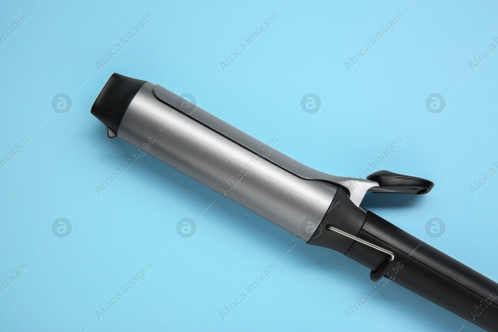 Photo of Hair styling appliance. One curling iron on light blue background, top view