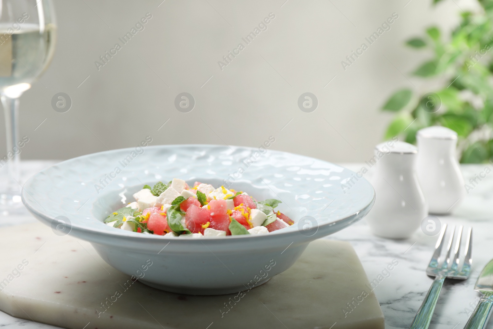 Photo of Delicious salad with watermelon, arugula and feta cheese served on white marble table