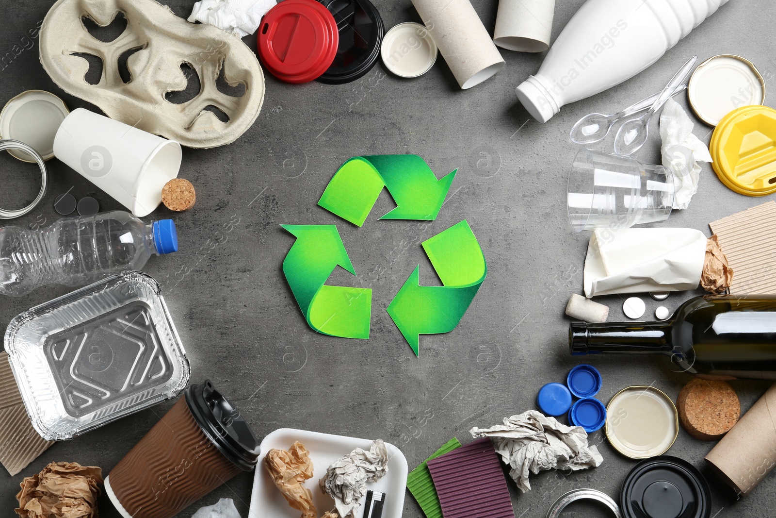 Photo of Recycling symbol and different garbage on gray background, top view