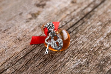 Photo of Heart shaped bottle of love potion with small key and padlock on wooden table