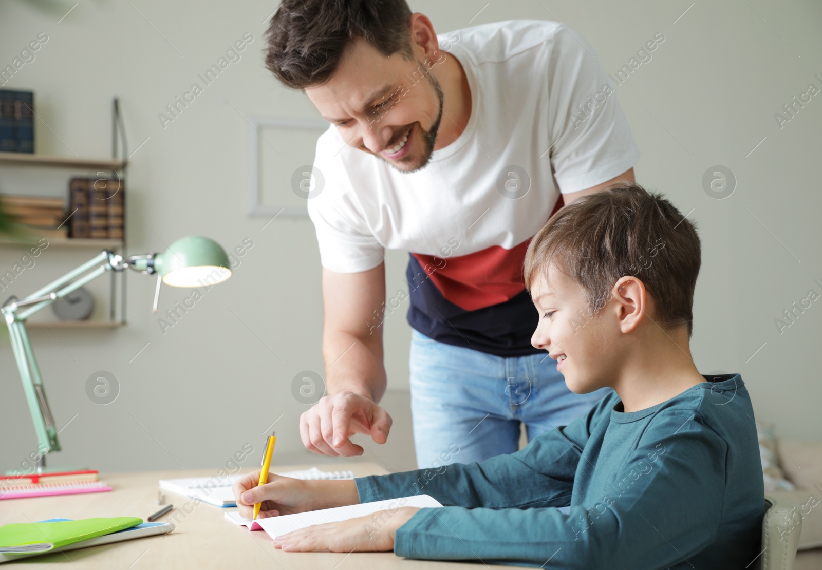 Photo of Dad helping his son with school assignment at home