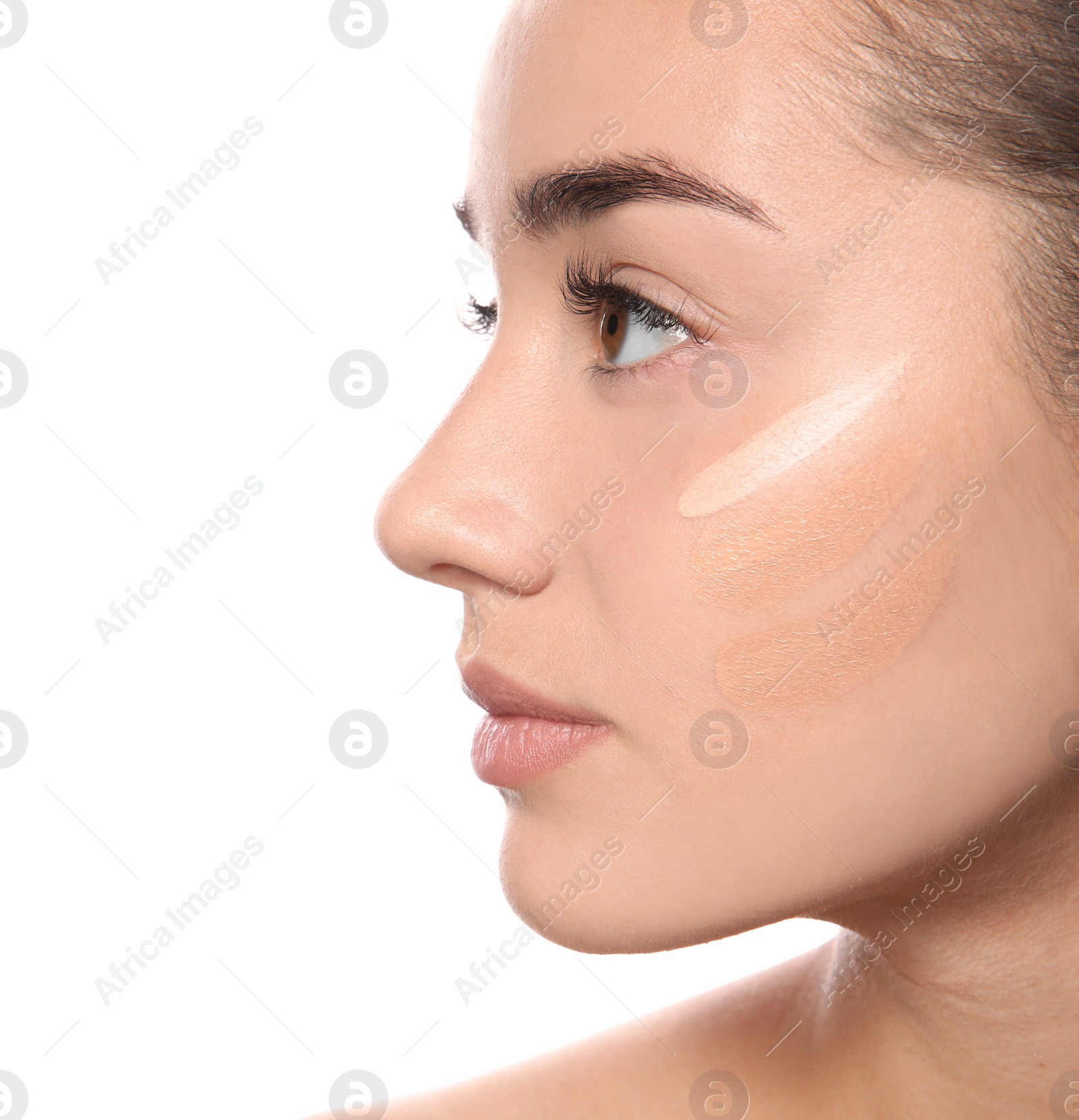 Photo of Young woman with different shades of skin foundation on her face against white background