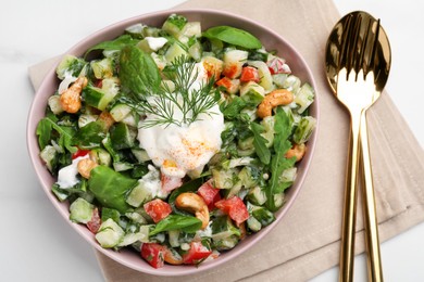 Bowl of delicious cucumber salad served on white marble table, flat lay