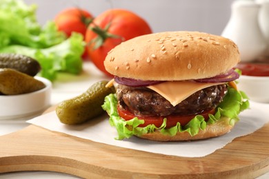 Photo of Tasty hamburger with patty, cheese and vegetables served on table, closeup