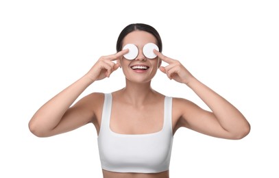 Young woman covering her eyes with cotton pads on white background