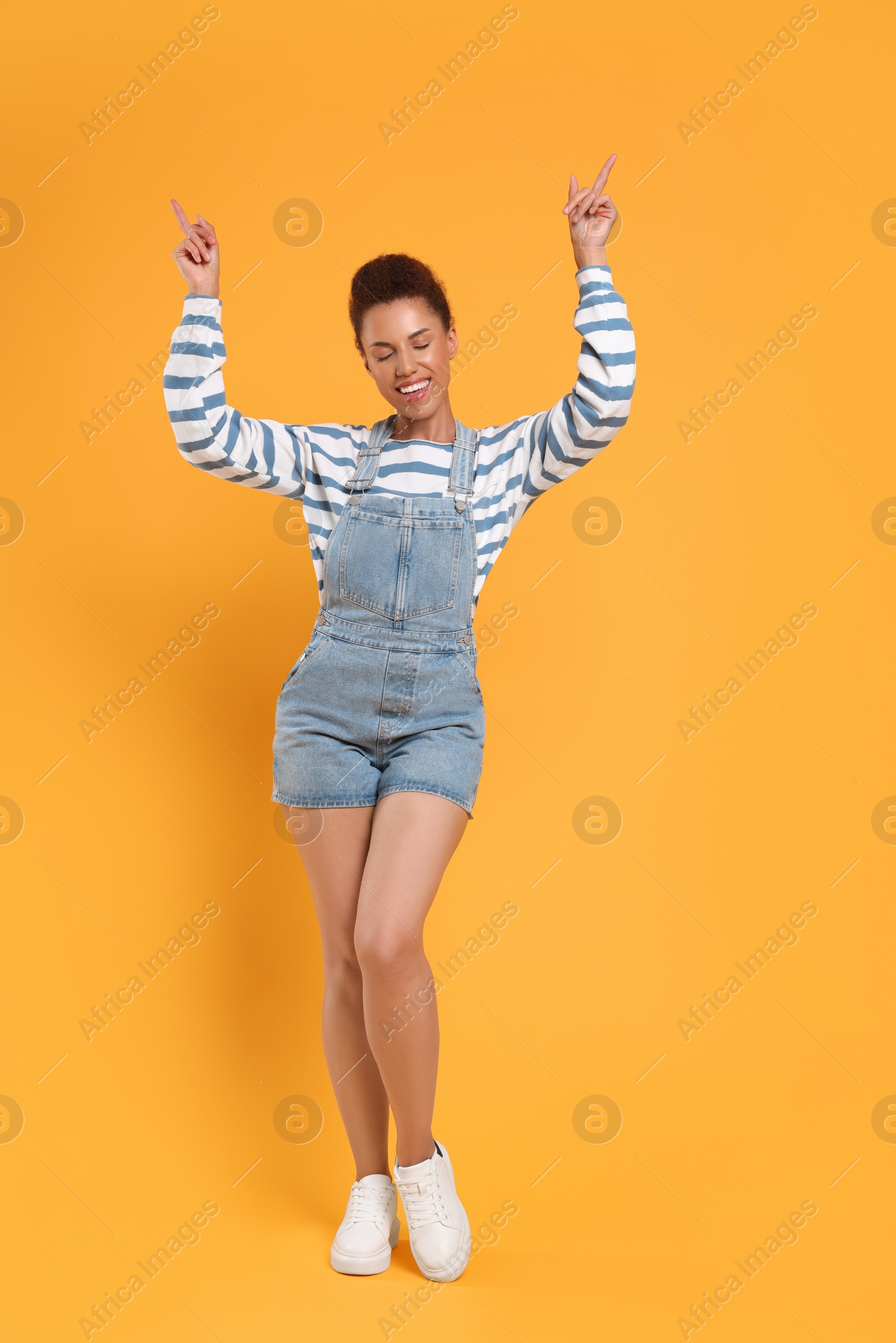 Photo of Happy young woman dancing on orange background