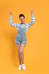 Photo of Happy young woman dancing on orange background